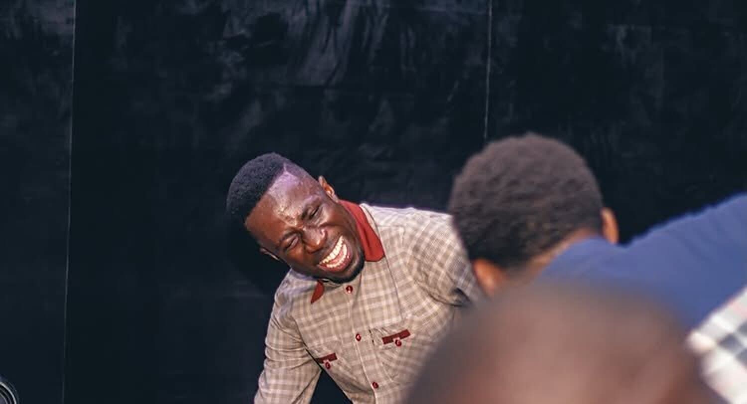 A minister laughing with joy beside the keyboard during praise