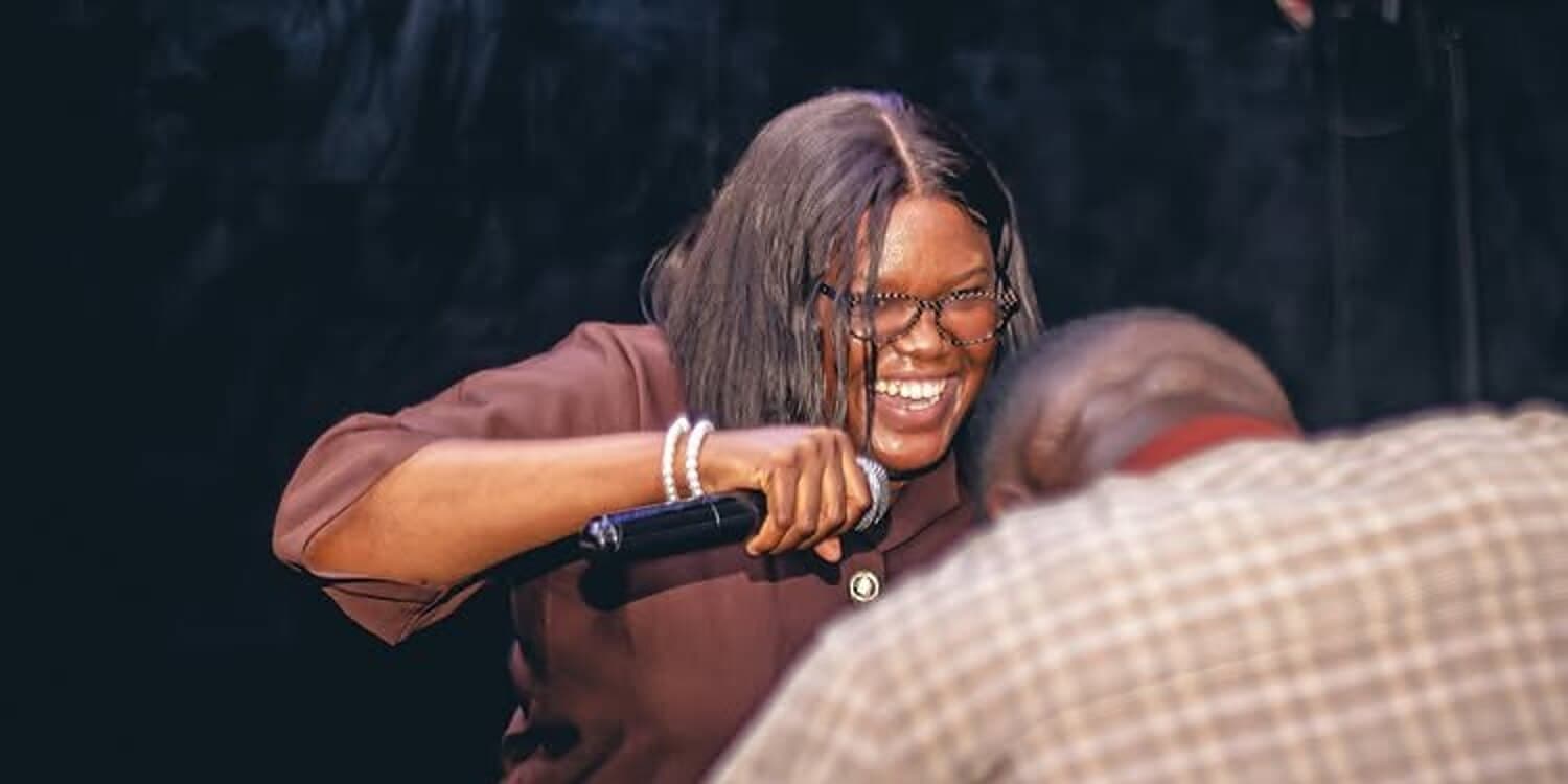 A singer laughing mid-song at a gathering